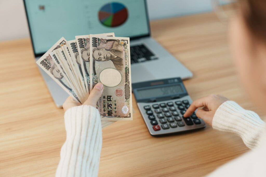Woman hand counting Japanese Yen banknote with calculator.