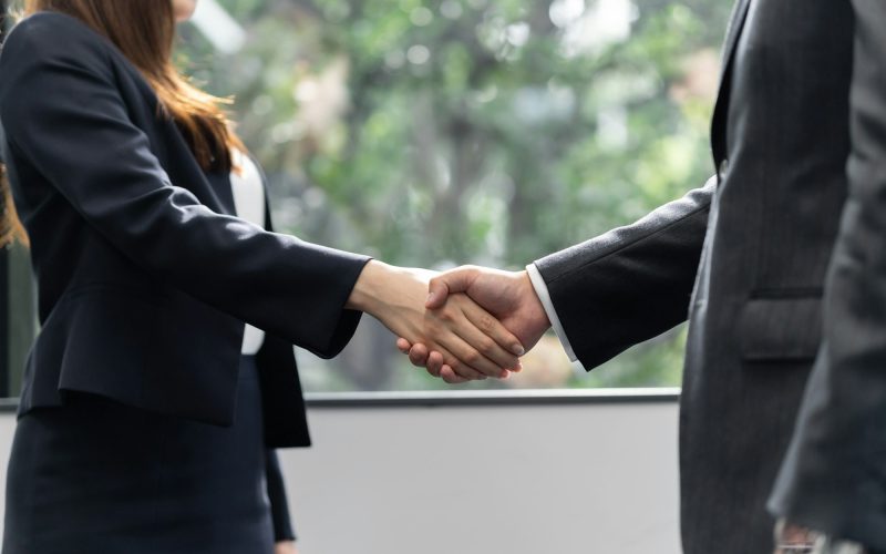 A handshake between a Japanese male businessman and a female businesswoman
